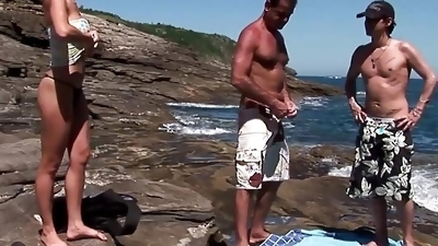 A hardcore double penetration threesome on a rocky beach makes the blonde happy and pleased